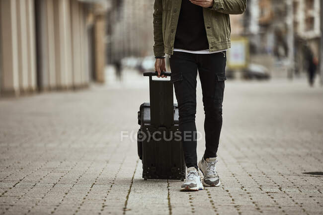 Man with suitcase walking on footpath — Stock Photo