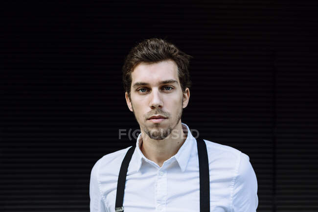 Retrato de un hombre de negocios elegante con camisa blanca y tirantes negros - foto de stock