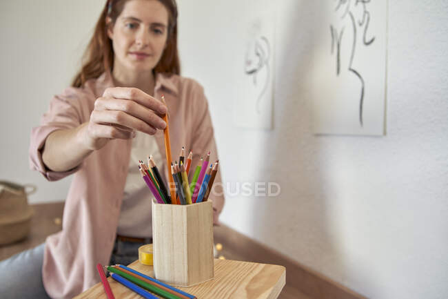 Artista femenina eligiendo lápiz de colores mientras trabaja en casa - foto de stock