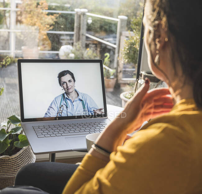 Female doctor smiling on laptop screen during video call — Stock Photo
