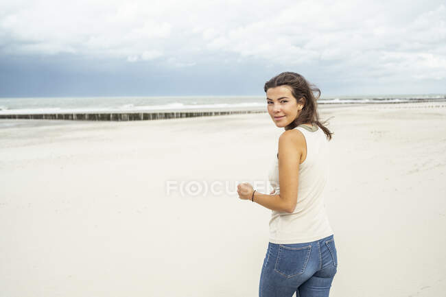 Giovane donna sorridente mentre cammina contro il cielo — Foto stock
