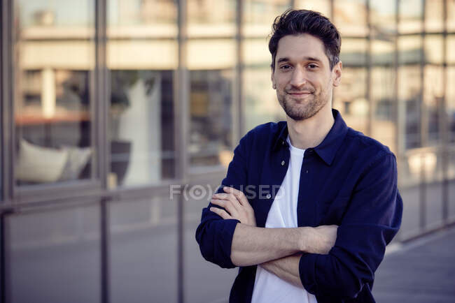Male entrepreneur smiling while standing with arms crossed outdoors — Stock Photo