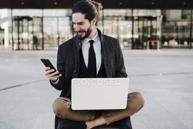 Geschäftsmann mit Laptop und Handy im Schneidersitz im Freien — Stockfoto