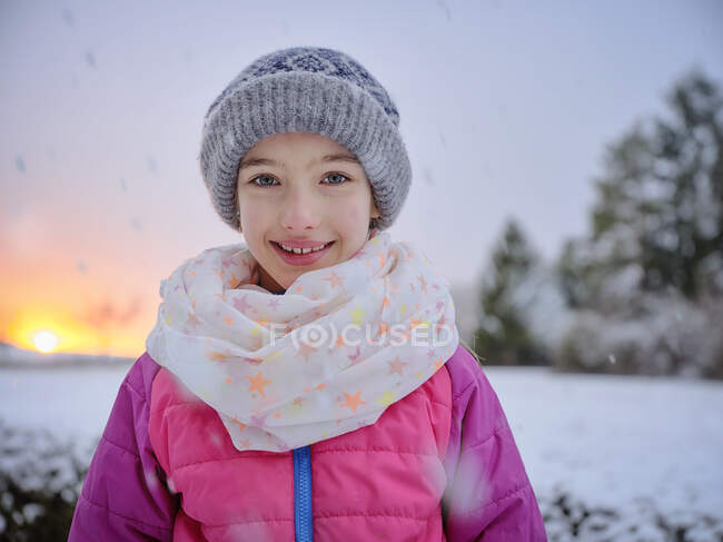 Cute smiling girl in warm clothing during sunset in winter — Stock Photo