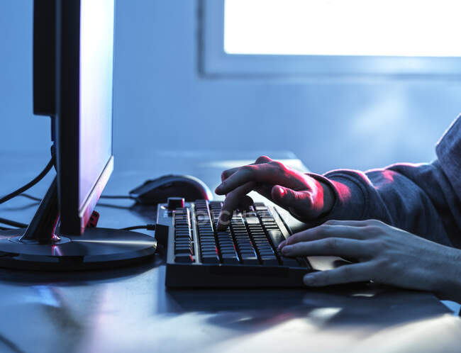 Hands of teenage boy breaching data from computer on desk — Stock Photo