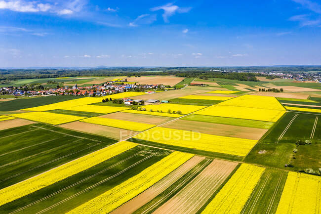 Germany, Hesse, Munzenberg, Helicopter view of countryside village and surrounding fields in summer - foto de stock