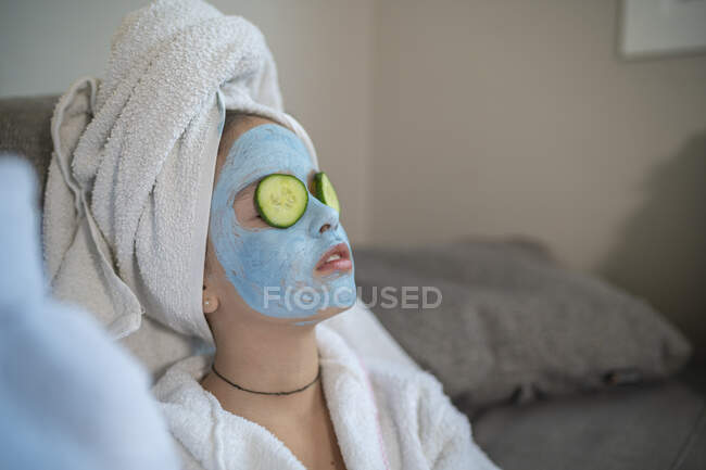 Girl with facial mask and cucumber slice on face — Stock Photo