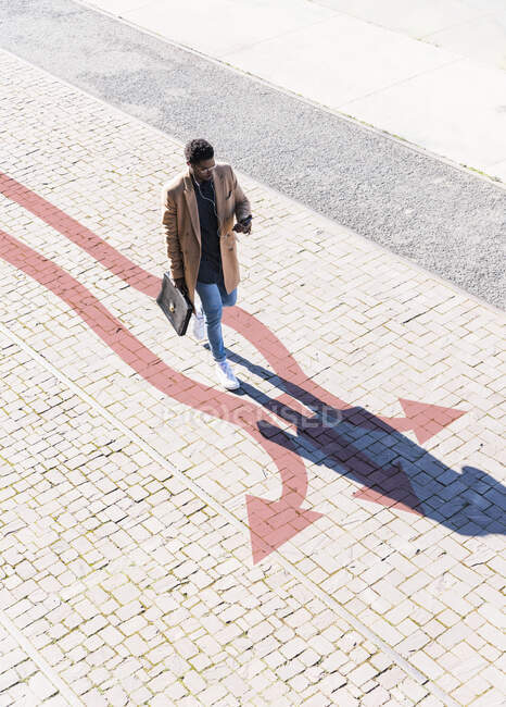 Well-dressed man walking along arrows stretching across sidewalk — Stock Photo