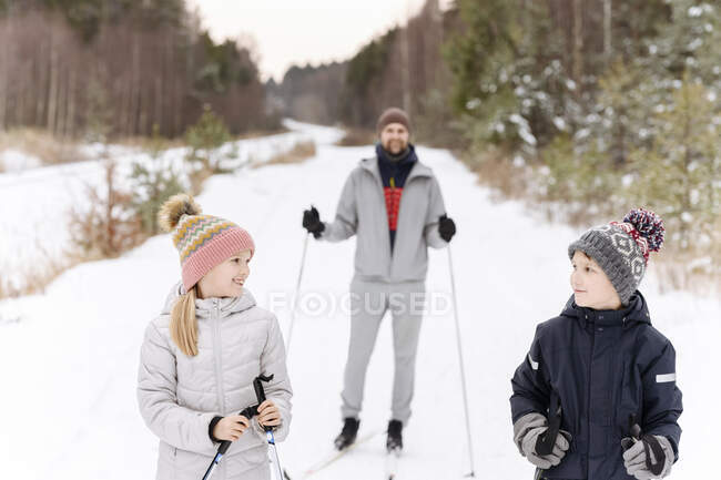 Père avec enfants skier sur un paysage enneigé en forêt — Photo de stock