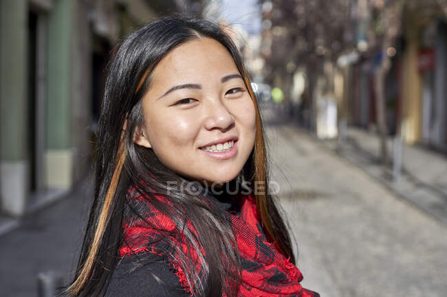Mujer sonriendo de pie en la calle de la ciudad - foto de stock