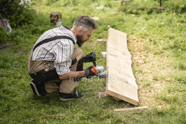 Tablón de molienda de carpintero con amoladora manual - foto de stock