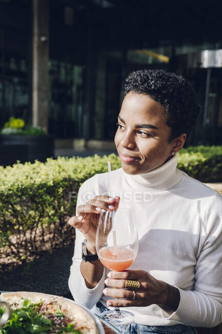 Smiling businesswoman day dreaming while drinking juice at restaurant during sunny day — Stock Photo