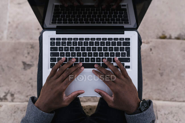 Homem usando laptop enquanto sentado em passos — Fotografia de Stock
