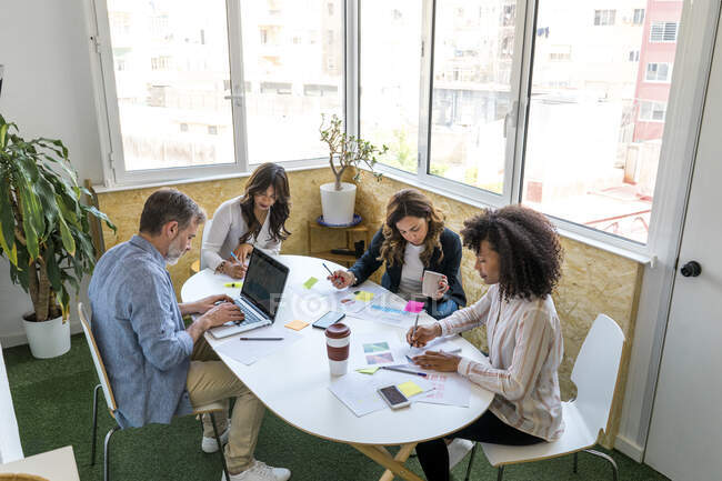 Colleghi uomini e donne seduti a tavola mentre lavorano in ufficio — Foto stock