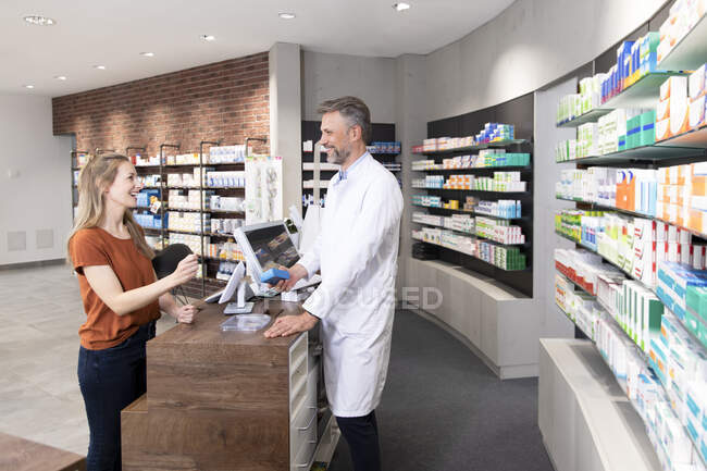 Female customer talking with pharmacist at pharmacy checkout — Stock Photo