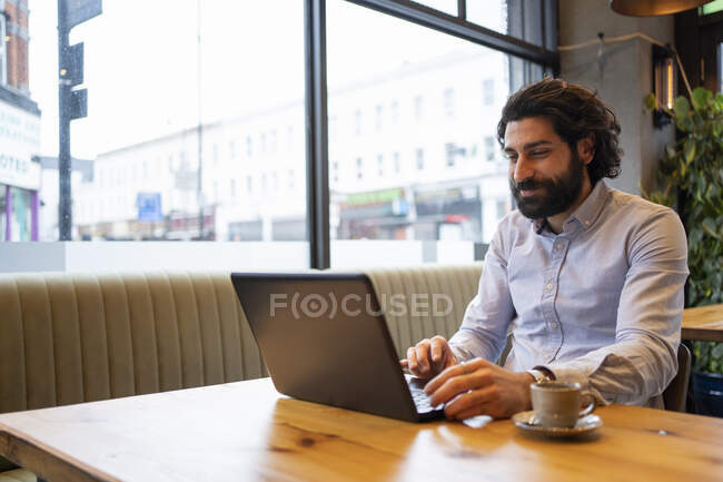 Bello uomo d'affari che utilizza il computer portatile mentre è seduto alla scrivania in ufficio — Foto stock
