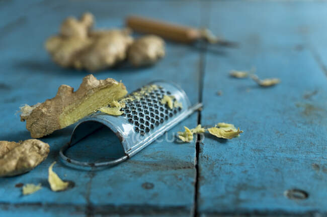 Ginger root and grater lying on blue wooden surface — Stock Photo