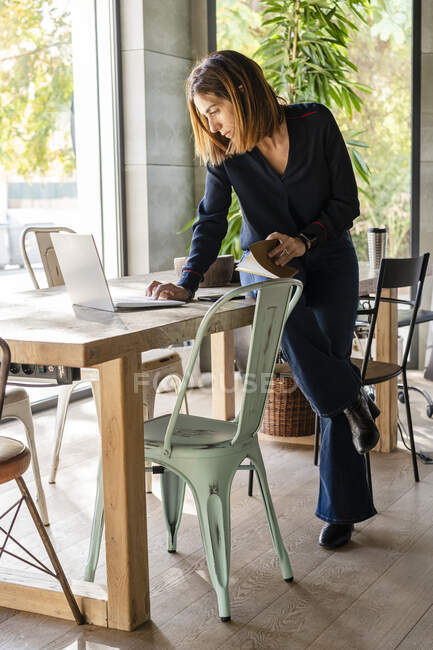 Imprenditrice donna che utilizza il computer portatile mentre è seduta sul tavolo da conferenza in ufficio — Foto stock