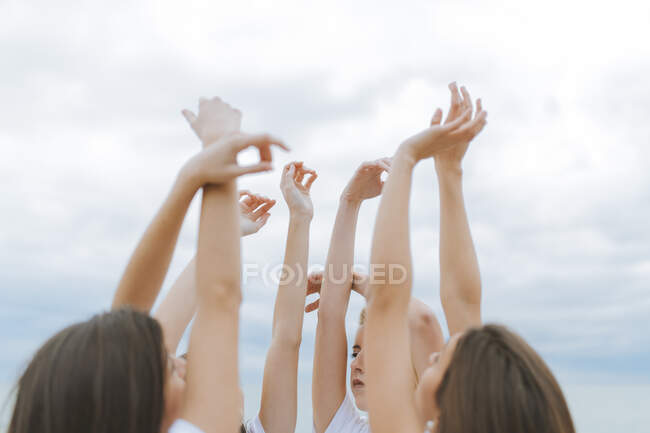 Female friends raising arms together against sky — Stock Photo