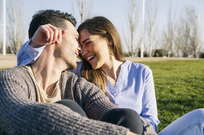 Novia sentada cara a cara con su novio en el parque - foto de stock
