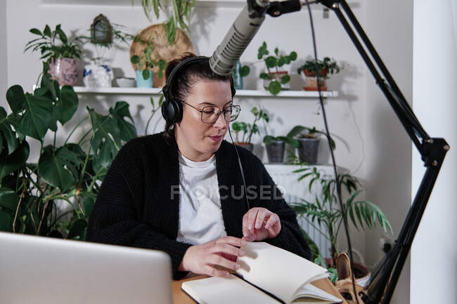 Femme faisant session podcast tout en étant assis contre la plante à la maison — Photo de stock