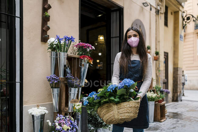 Mujer joven sosteniendo cesta de flores de hortensias en la tienda —  ventana, Pantalla de ventana - Stock Photo | #482782470