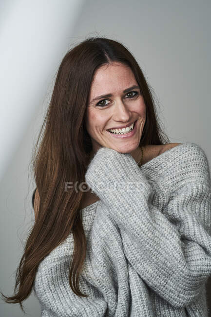 Счастливая женщина среднего возраста в свитере на сером фоне — стоковое фото