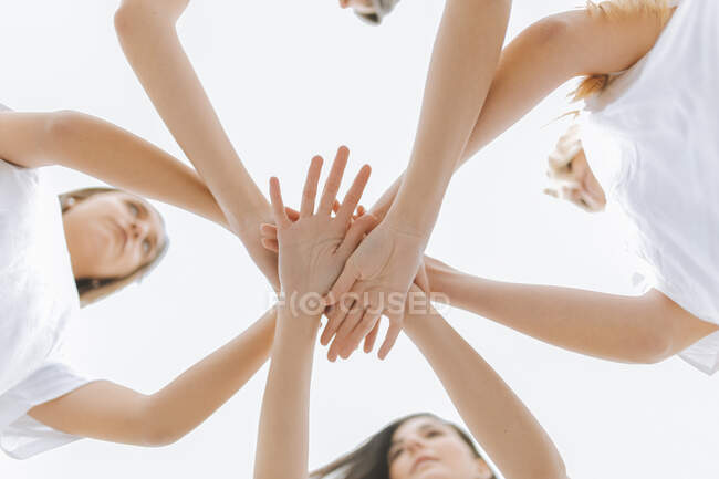 Giovani amiche con mani impilate contro il cielo — Foto stock