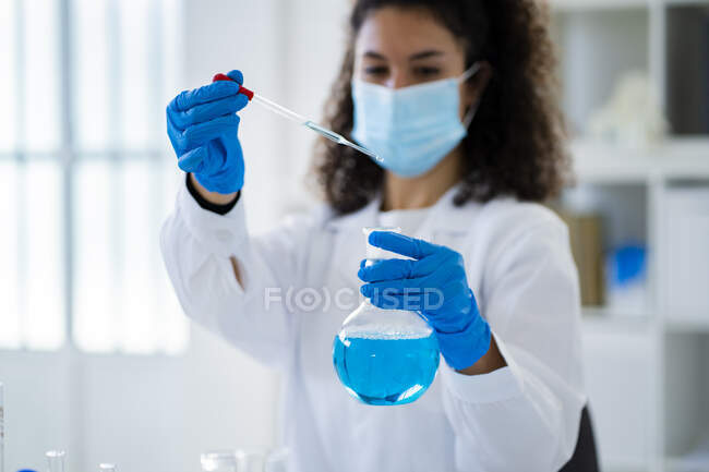 Giovane medico donna prova soluzione chimica in ospedale durante la pandemia — Foto stock