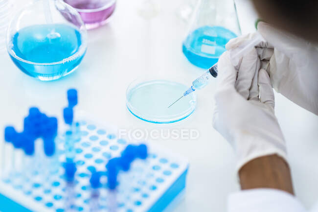 Researcher drawing liquid from petri dish in syringe at laboratory — Stock Photo