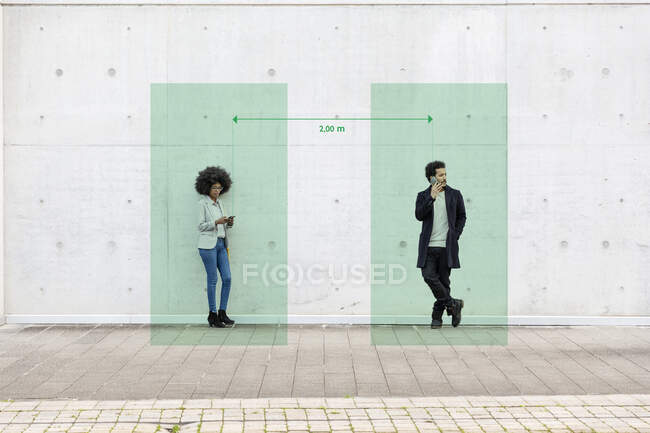 Rectangles visualizing social distancing covering man and woman standing outdoors with smart phones in hands — Stock Photo