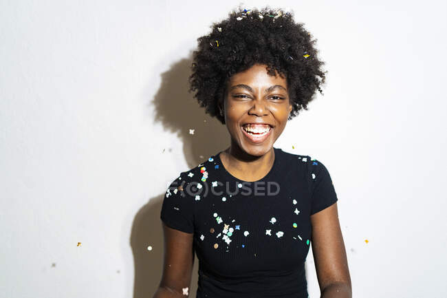 Кучеряве волосся жінка сміється, стоячи на білому тлі — стокове фото
