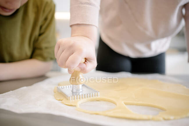 Mädchen mit Holzgriff Ausstecher auf Teig in Küche beim Betrachten — Stockfoto