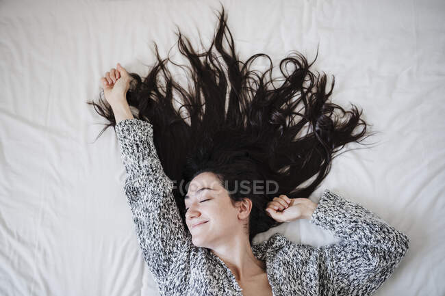 Unbekümmerte Frau mit langen Haaren liegt zu Hause im Bett — Stockfoto