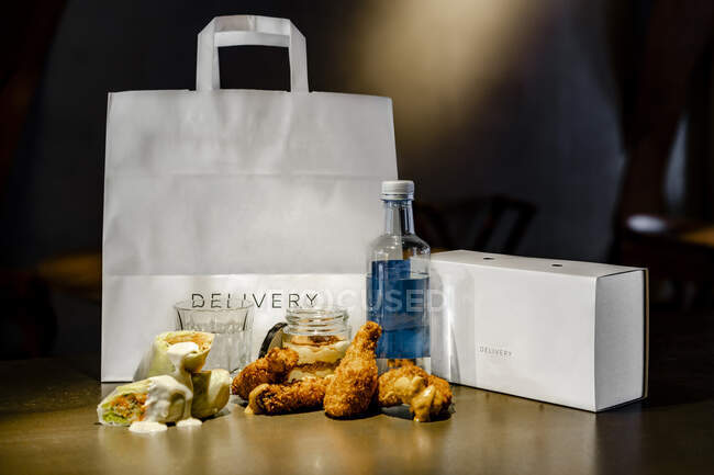 Куриные крылышки и сэндвич по доставке сумки и коробки на острове кухни — стоковое фото