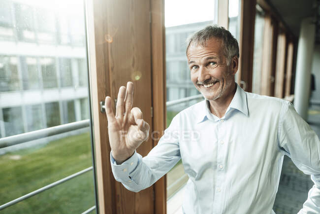 Happy male entrepreneur gesturing while standing by window in office — Stock Photo