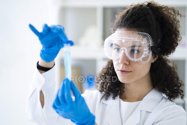 Investigadora que examina solución química en tubo de ensayo en laboratorio - foto de stock