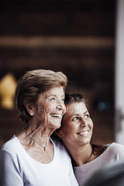 Glückliche Seniorin und Enkelin umarmen sich beim Wegschauen — Stockfoto