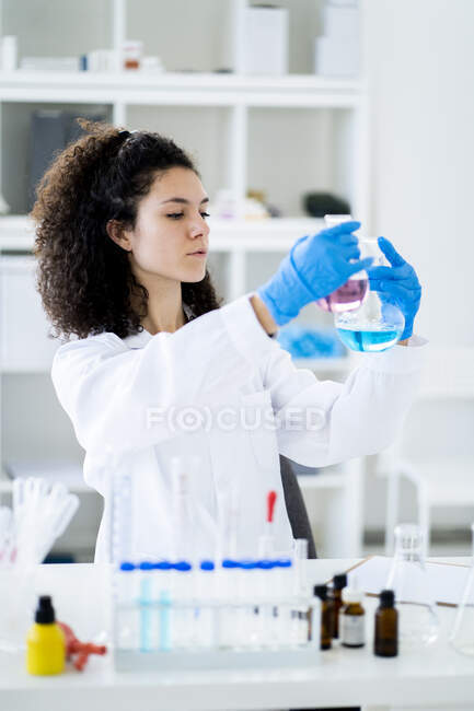 Giovane ricercatrice che sperimenta una soluzione chimica in becher in ospedale — Foto stock