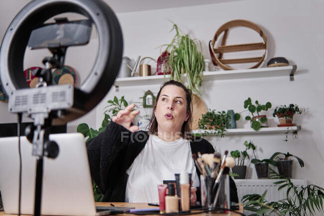 Femme mature vlogger gestuelle tout en enregistrant tutoriel maquillage à la maison — Photo de stock