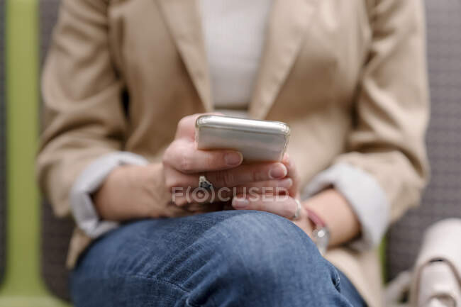 Mulher segurando telefone celular enquanto sentado na estação de metrô — Fotografia de Stock