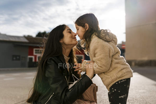 Дочка терла ніс з мамою, стоячи на дорозі. — стокове фото