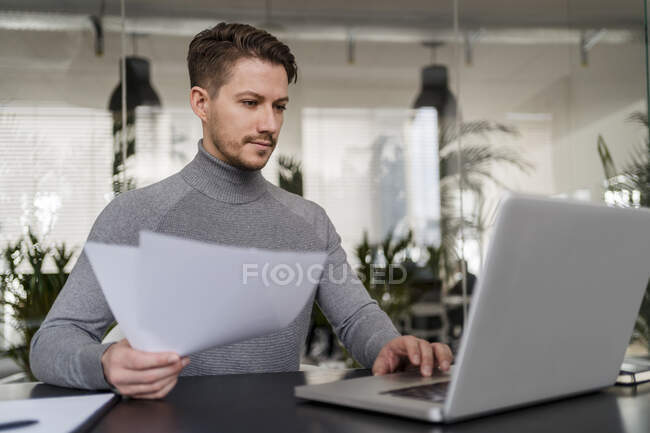 Homme d'affaires confiant travaillant sur ordinateur portable au bureau — Photo de stock