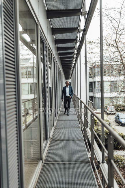 Homme d'affaires regardant loin tout en marchant dans le balcon du bureau — Photo de stock