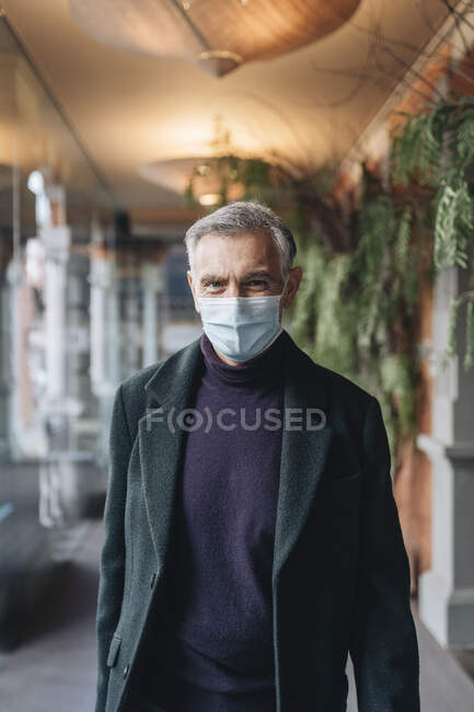 Man in jacket and protective face mask at hotel corridor — Stock Photo
