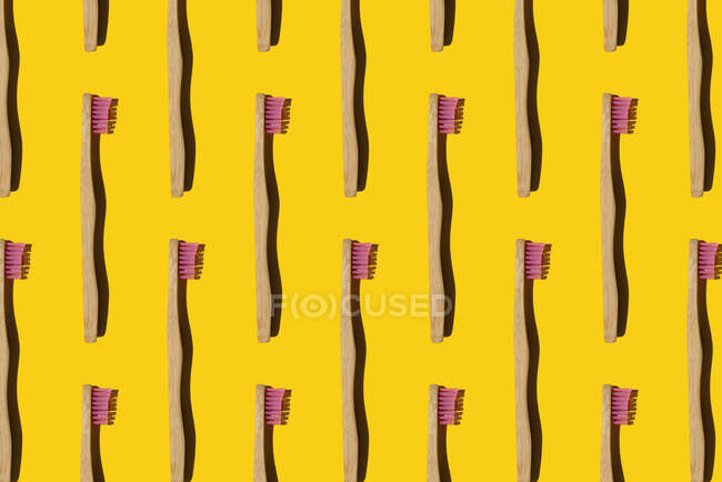 Digitally generated pattern with bamboo toothbrushes on yellow background — Stock Photo
