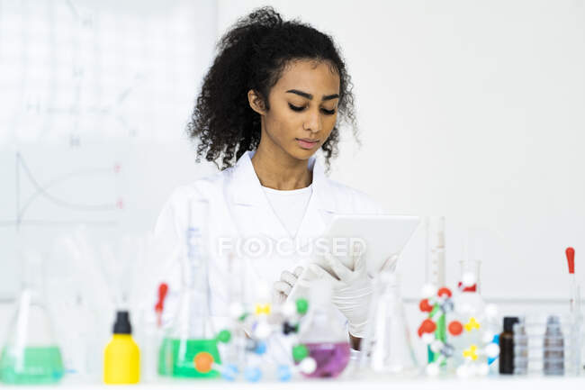 Jovem química do sexo feminino trabalhando em tablet digital em laboratório — Fotografia de Stock