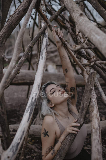 Donna bionda con gli occhi chiusi tenendo ramo di albero nudo — Foto stock