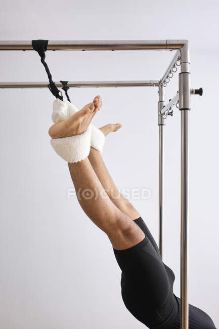 Hombre adulto medio estirando las piernas en la máquina de pilates en el gimnasio - foto de stock