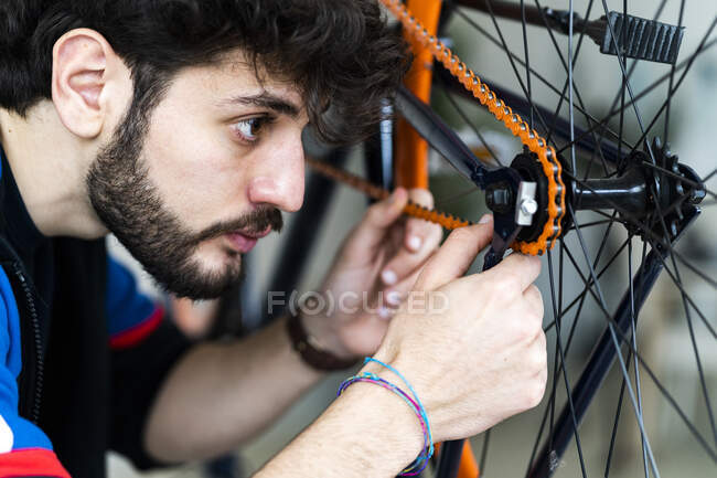 Konzentrierter junger Mann untersucht Fahrradkette zu Hause — Stockfoto
